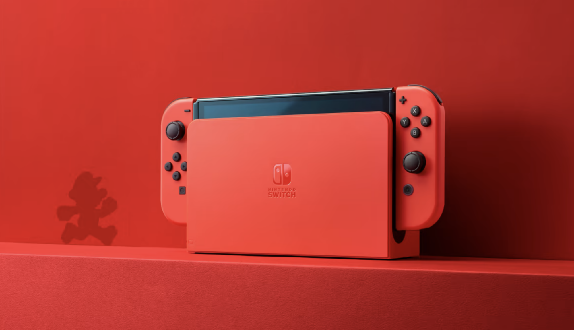 nintendo switch oled model in mario red edition against red wall with Mario shadow